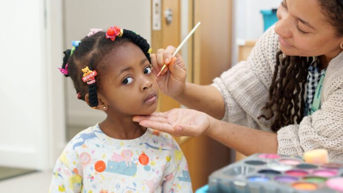 A young girls getting her face painted at a Children and Family Hub.