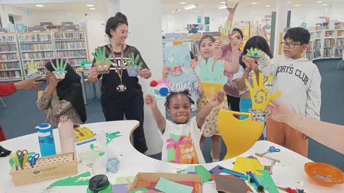 Young people at a library posing with the arts and crafts they created.
