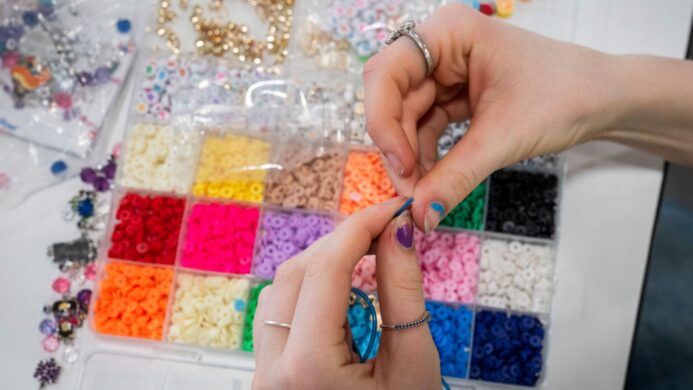 A close up of a young woman's hands creating a bracelet.