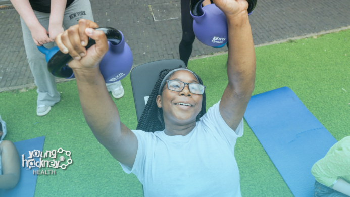 A young woman raising kettle bell weights above her head